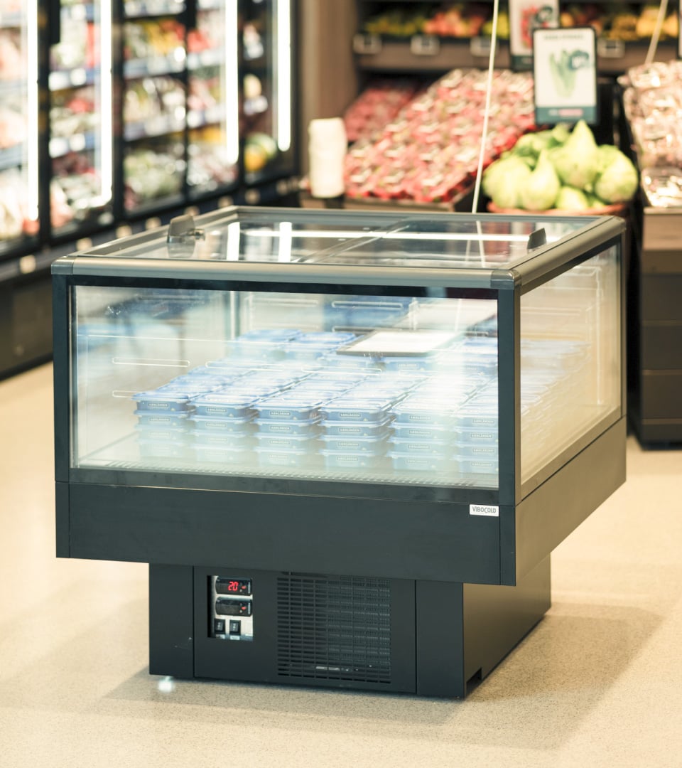 Køledisk med glaskasse fyldt med blå pakker i dagligvarebutik